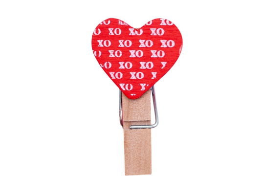 A single red heart with xo pattern attached to a wooden clothespin on a black background close up view