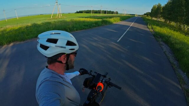 man riding bike at sunset outside city and filming video for blog, solo bike trip