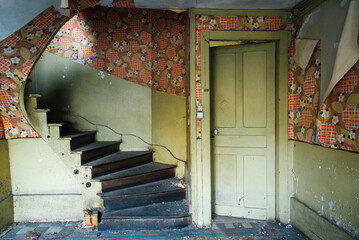 Ancienne montée d'escaliers en bois dans une vieille maison abandonnée. Papier peint déchiré...