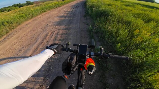 Cycling on a dirt country road in summer in a field at sunset