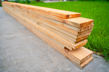 Wooden boards for construction stacked on a background of green grass, close-up