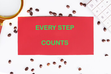 Concept text EVERY STEP COUNTS written on red paper on a work surface surrounded by coffee beans...