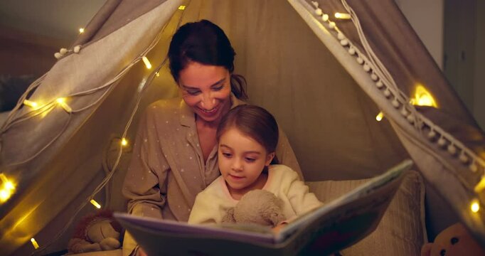 Tent, child and mother reading book in home for bedtime story, learning and talk. Storytelling, parent and girl relax with fairytale at night for education, teaching or bonding with happy family