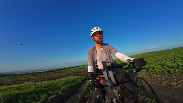 man riding bike at sunset outside city and filming video for blog, solo bike trip