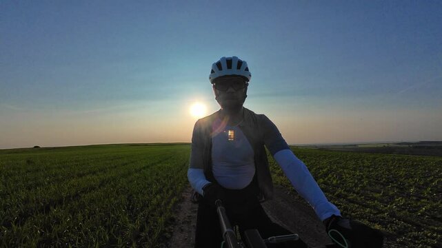 man riding bike at sunset outside city and filming video for blog, solo bike trip