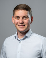 Obraz premium Studio shot of young man wearing classic white dress shirt, looking directly at camera. Concept of confidence, business, fashion, or lifestyle themes.