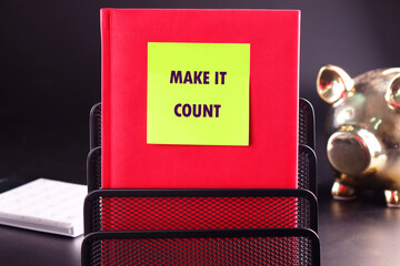 MAKE IT COUNT words written on a yellow sticker stuck on a red business notebook
