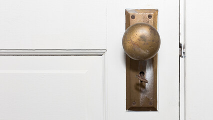 Close-up color photo of an old vintage round doorknob with a skeleton key in the keyhole against a...