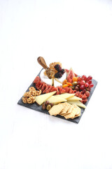 Gourmet charcuterie and cheese board on slate. Assorted cheeses, cured meats, fruits, nuts, and crackers