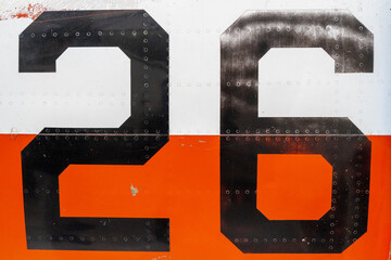 Black number -26- on an old aircraft fuselage with riveted panels
