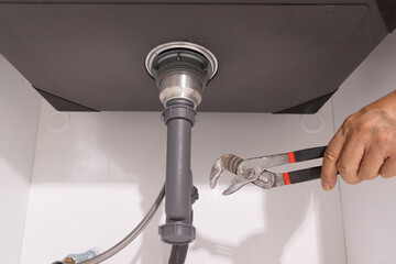 Plumber open trap to fixing drain clog under sink.