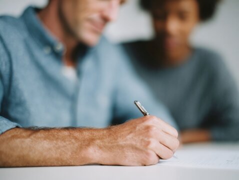 Interracial couple signing document together at table