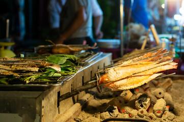 Grilled fish cooking over charcoal at night market