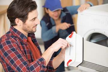 male and female service agents repairing a washing machine