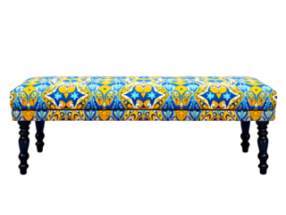 Long upholstered bench with ornate blue and yellow pattern on a black background in studio setting