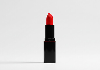 Obraz premium A sleek black tube of red lipstick standing upright against a plain white background in a studio shot