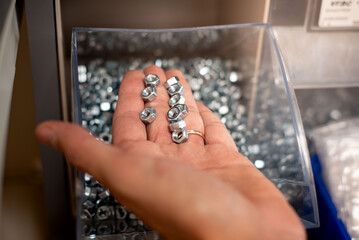  Close-up of male hands picking screws from a shelf in a hardware store. Focus on selection process and DIY planning.