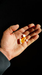 Pills, medicine and healthcare of senior man taking daily capsules and pills. Close up hand man taking multiple pills take a medicine in hand
