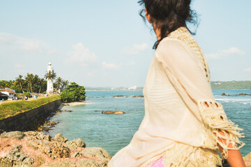 Woman tourist sit enjoy panoramic Lookout from UNESCO Galle Fort. Galle Fort Walk with Ocean Views concept. Sightseeing landmark and popular visit destination in Sri lanka