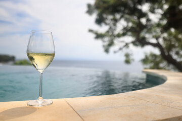 a glass of white wine on the background of the pool, relaxing at the hotel