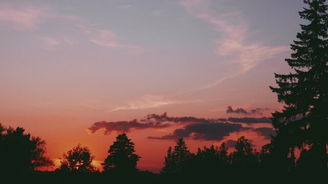 Evening sky at sunset background in forest. Dark clouds hanging above horizon. Majestic cloudscape in blue, orange, violet shades. Grey cloudlets bringing rain. Countryside skyline in twilight time
