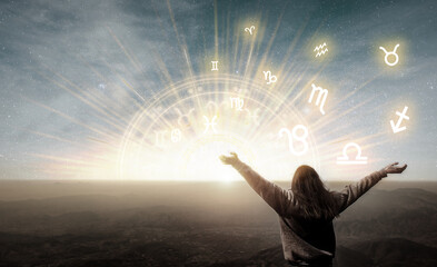 Woman raising hands looking at the sky. Astrological wheel, choose a zodiac sign. Astrology and horoscopes concept.