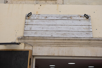 Blank weathered wooden signboard mounted above shop entrance. Vintage texture, urban signage, and rustic commercial exterior.