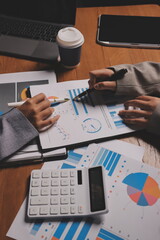 Group of confident business people point to graphs and charts to analyze market data, balance sheet, account, net profit to plan new sales strategies to increase production capacity.