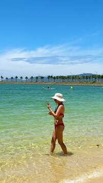 Beautiful girl in pink swimsuit posing on the beach, taking pictures and photos, slim figure, girl in red ikini, clean ocean, beautiful beach