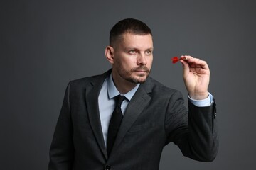 Targeting. Man with dart aiming on grey background