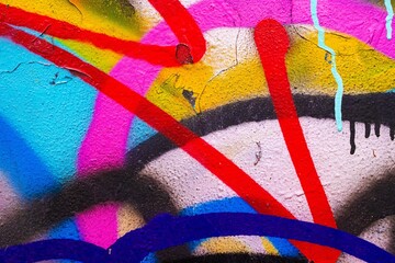 Colorful graffiti with vibrant red, blue, yellow on textured wall. Bold 80s style, neon accents,...