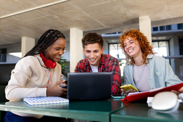 University students collaborating on project using laptop and smart phones