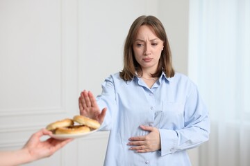 Gluten free diet. Woman refusing from pretzels indoors