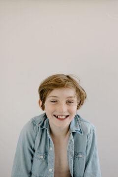 Laughing boy in chambray shirt on white backdrop