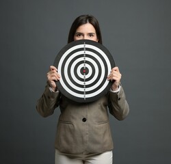 Targeting. Businesswoman with dart board on grey background