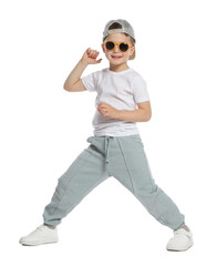 Happy little boy in sunglasses and baseball hat dancing on white background