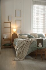 Comfortable bed with soft linens, lamp and decor in stylish room. Home textile