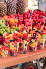 Fresh fruit salad cups on mobile cart with berries and tropical fruits