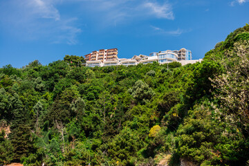 Modern buildings hotel on a lush green hillside under clear summer sky. Architecture, nature, and elevated coastal real estate concept.