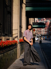 Portrait of handsome Chinese young man wearing gray suit posing in the street, young guy with black curly hair with urban background. Male fashion, cool Asian young man lifestyle.