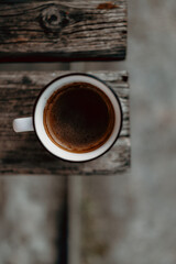 Flat lay of white coffee cup on rustic wooden board in morning garden light. Cozy cottagecore style with warm tones and peaceful outdoor ambiance.
