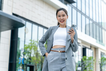Young adult business working asian woman using digital tablet for online application on day.Asia Business female standing or walking on big city urban street outside.City Streets With People concept