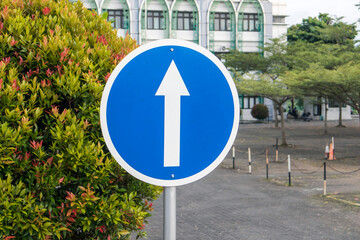Go straight ahead round blue traffic sign. Close-up of blue and white one way road sign with white...