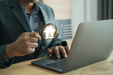 Business Professional Using Laptop to Access Real Estate Software with Home Icon and Data Analytics in Modern Office Environment