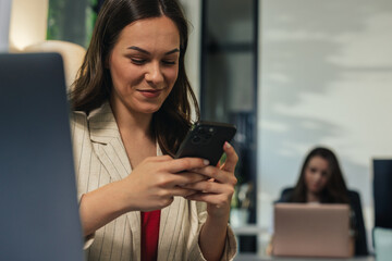 Obraz premium Young businesswoman using smartphone in modern office workplace