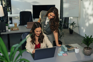 Two Businesswomen Collaborating on a Laptop in a Modern Office