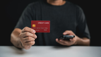 Person Holding Credit Card and Smartphone in Front of Black Background Showcasing Contactless Payment Technology and Online Shopping Experience