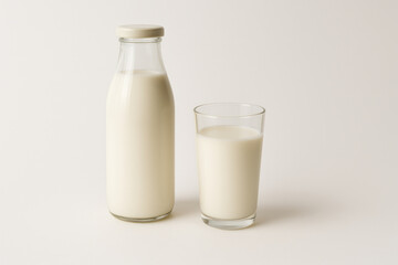 Glass and bottle of milk on white background.