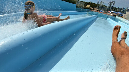 A close-up shot of a family enjoying a thrilling water slide at an aqua park. The perspective...