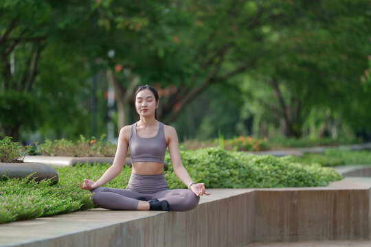 Young asian woman doing yoga meditation in a peaceful green park